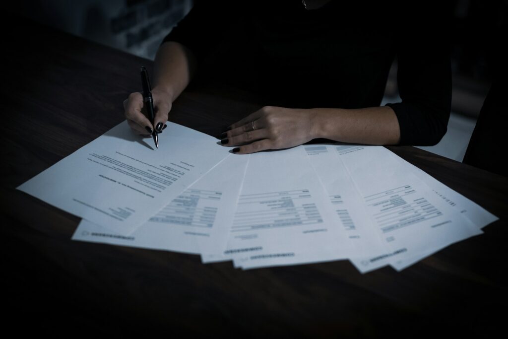 Persona revisando y firmando documentos de facturación sobre una mesa